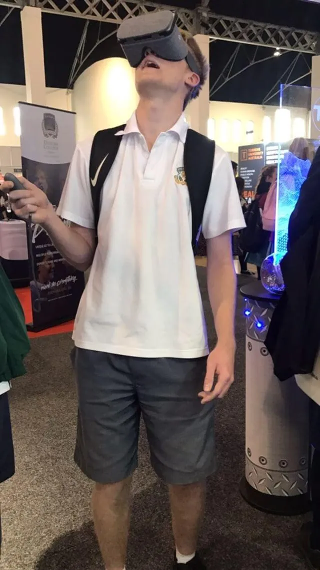 A photo of a high school student playing a game in a VR headset, mouth open wide as they’re enthralled by the virtual world that they are definitely saving from the aliens - not at all just watching a blaze of virtual destruction, we hope!